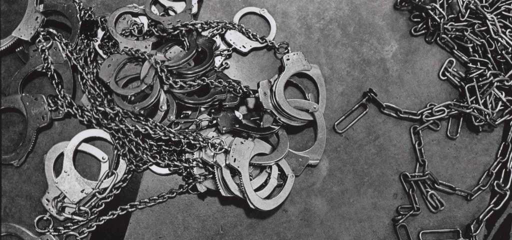 A black and white photo of a pile of handcuffs and chains.