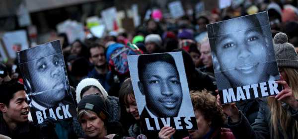 Protesters hold three signs that read Black Lives Matter with pictures of Michael Brown, James Garner, and Tamir Rice.