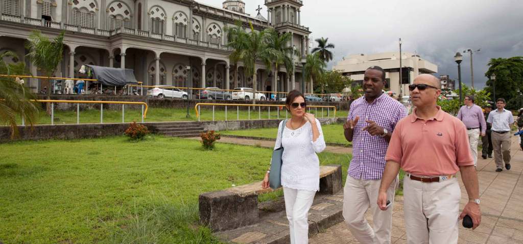 Darren Walker and two colleagues walk past a green lawn and ornate building in Quibdo, Colombia.