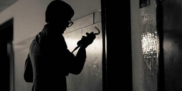 Man holding a crow bar getting ready to break into a room