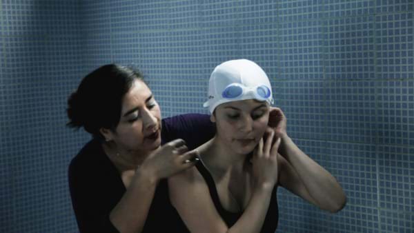 Mother helping her daughter put on swimming cap. This image is unavailable under the 4.0 Creative Commons license.