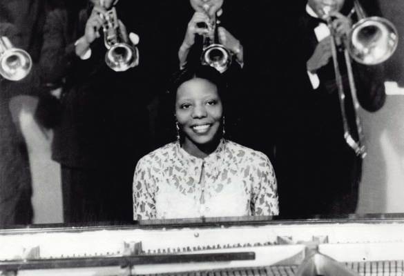 Mary Lou Williams at the piano and in front of a band. This image is unavailable under the 4.0 Creative Commons license.