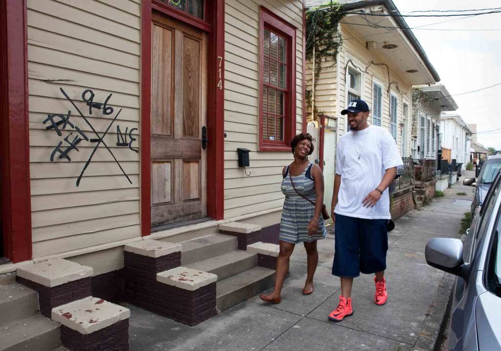 Winins and Hallershorn walk on a street in front of a house stoop with markings on it.