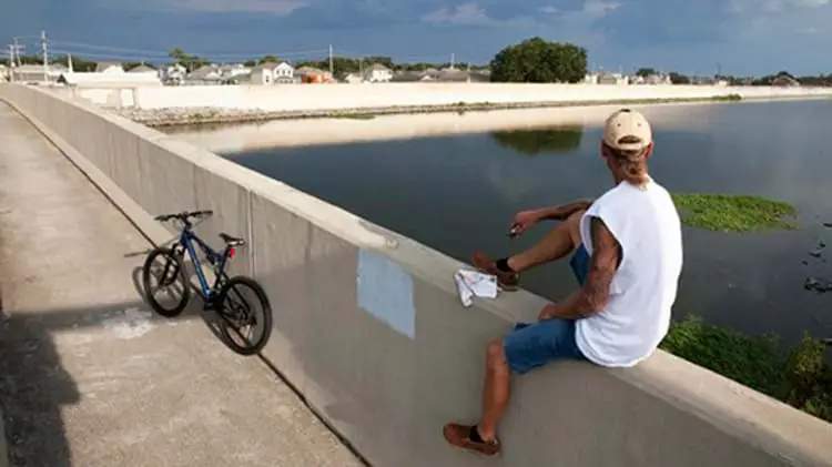 Dean Marshall sits on a concrete wall and looks at the 17th Street Canal and flood wall in New Orleans.