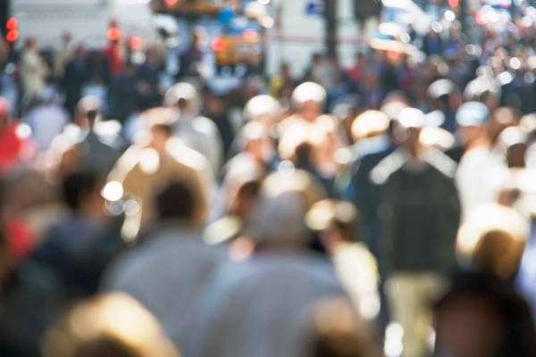A blurry photo of a crowd of people walking on Fifth Avenue in New York. 