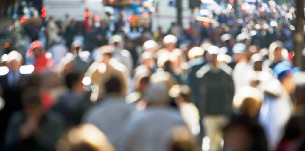 A blurry photo of a crowd of people walking on Fifth Avenue in New York.