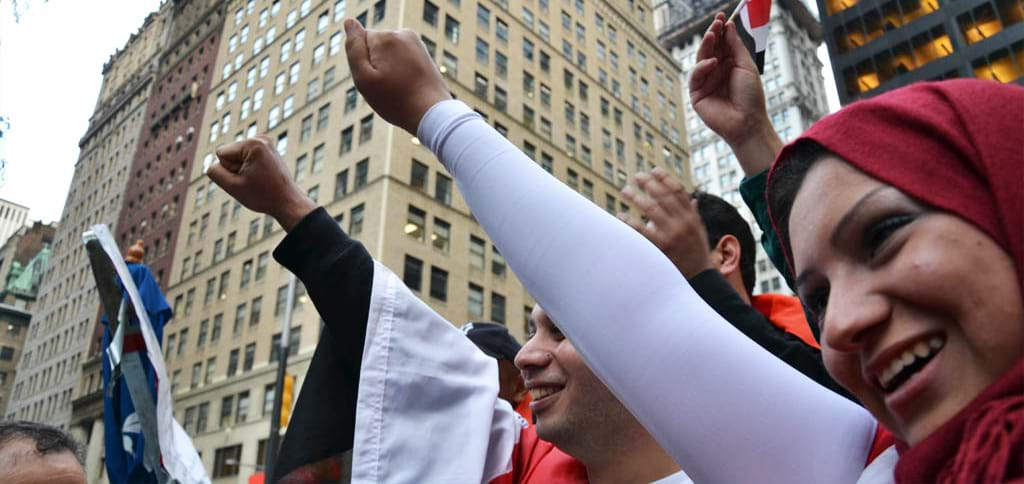 People demonstrating on city street with smiles and raised fists