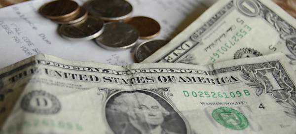 A close up shot of a $1 bill and change on top of a receipt.