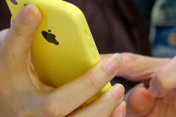 Close up of a person's hands holding a yellow iPhone. 