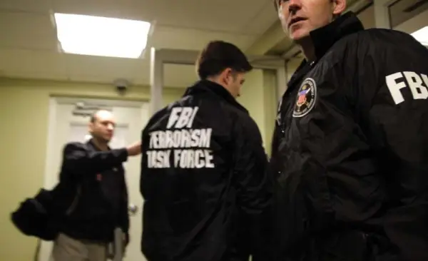 Agents in FBI jackets in hallway. Still from "(T)error". 2016. This image is not available under the 4.0 Creative Commons license.