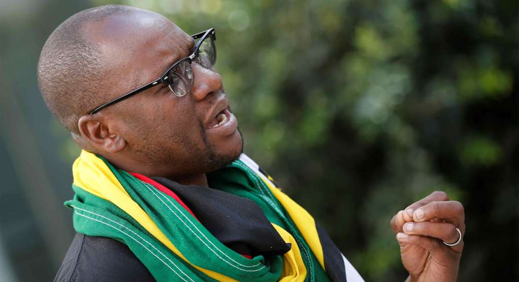 Pastor Evan Mawarire speaks during his interview with Reuters in Johannesburg. He is wearing glasses and a green, yellow, and red scarf.