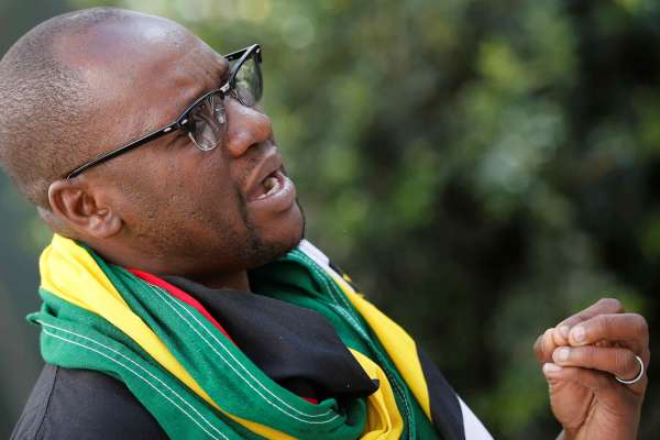 Pastor Evan Mawarire speaks during his interview with Reuters in Johannesburg. He is wearing glasses and a green, yellow, and red scarf. 