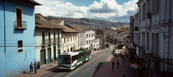 A white and green bus drives down a street in Quito, Ecuador. 