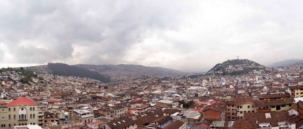 A wide shot of the Quito, Ecuador cityscape under a grey cloudy sky.