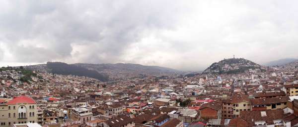 A wide shot of the Quito, Ecuador cityscape under a grey cloudy sky.