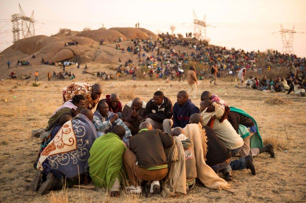 Miners in Marikana huddle and strategize during their strike for a living wage in 2012. Credit: Greg Marinovich