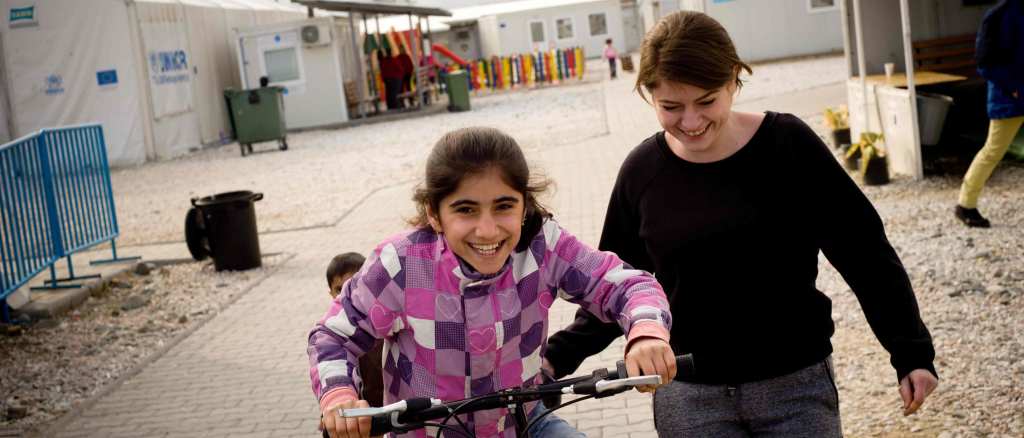 A teacher of the Temporary Transit Center of Gevgelija in south Macedonia helps a refugee girl ride a bike.