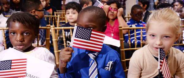 Children wave American flags after taking the Oath of Allegiance as they become U.S. citizens at a ceremony in New York. Credit: Anthony Behar/Sipa USA