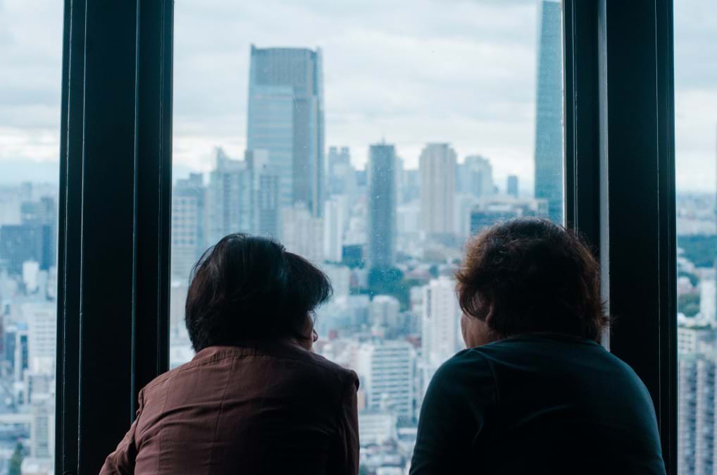 Two people staring out a skyscraper window