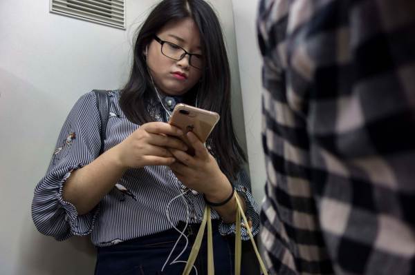 A woman uses a smart phone while riding the subway. Photo by Zhang Peng/LightRocket via Getty Image
