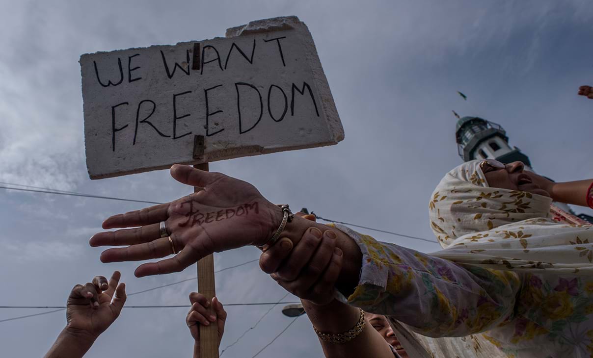Women protesters in India are holding a sign that reads "We want freedom" and a woman with the word "freedom" written on her hand.