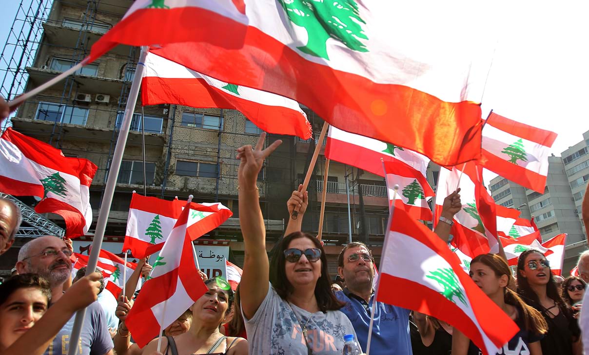 Lebanese demonstrators raise national flags in protests against a proposed tax on mobile messaging applications.