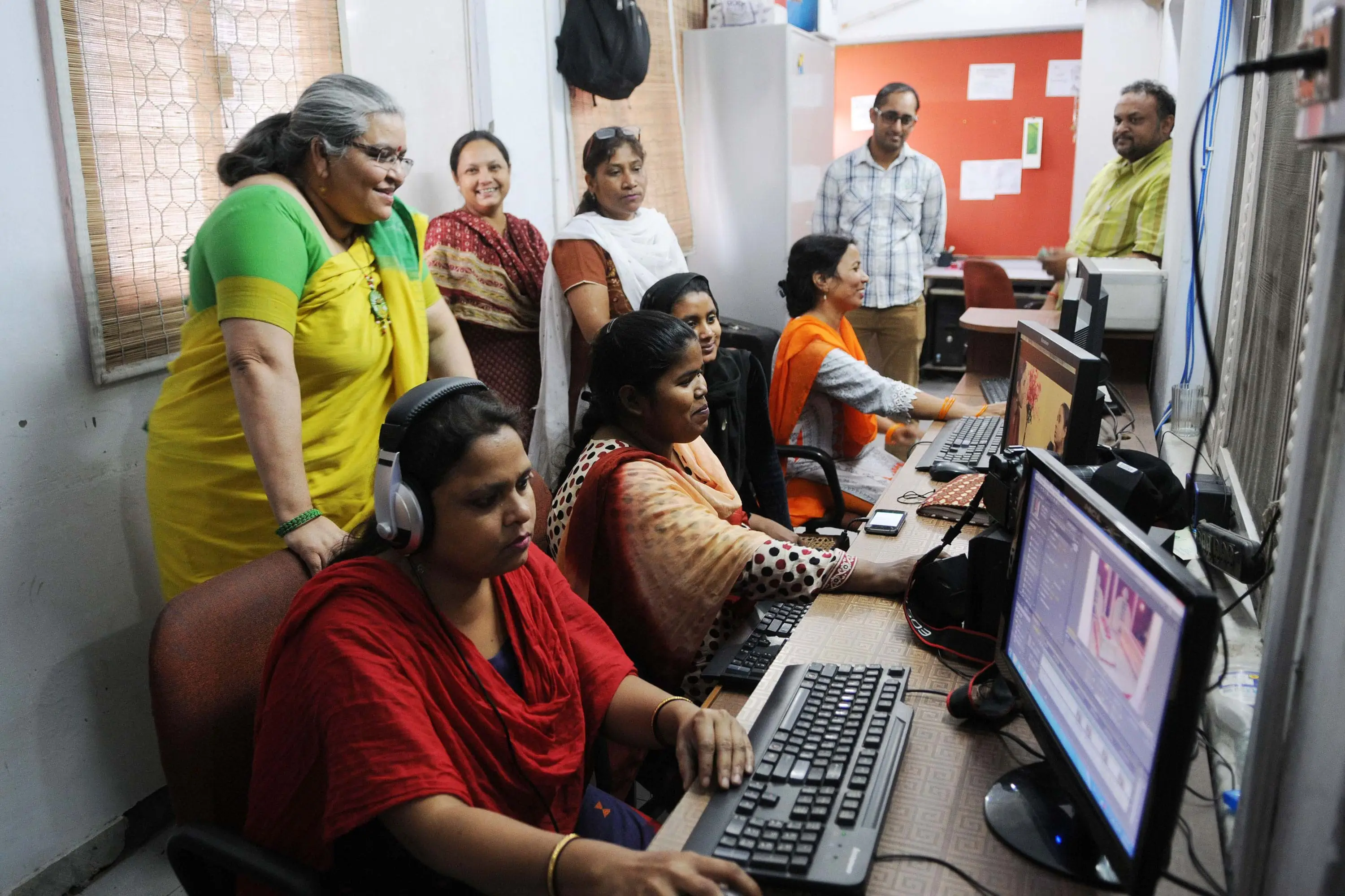 South Asian women sit at computers in an office. 