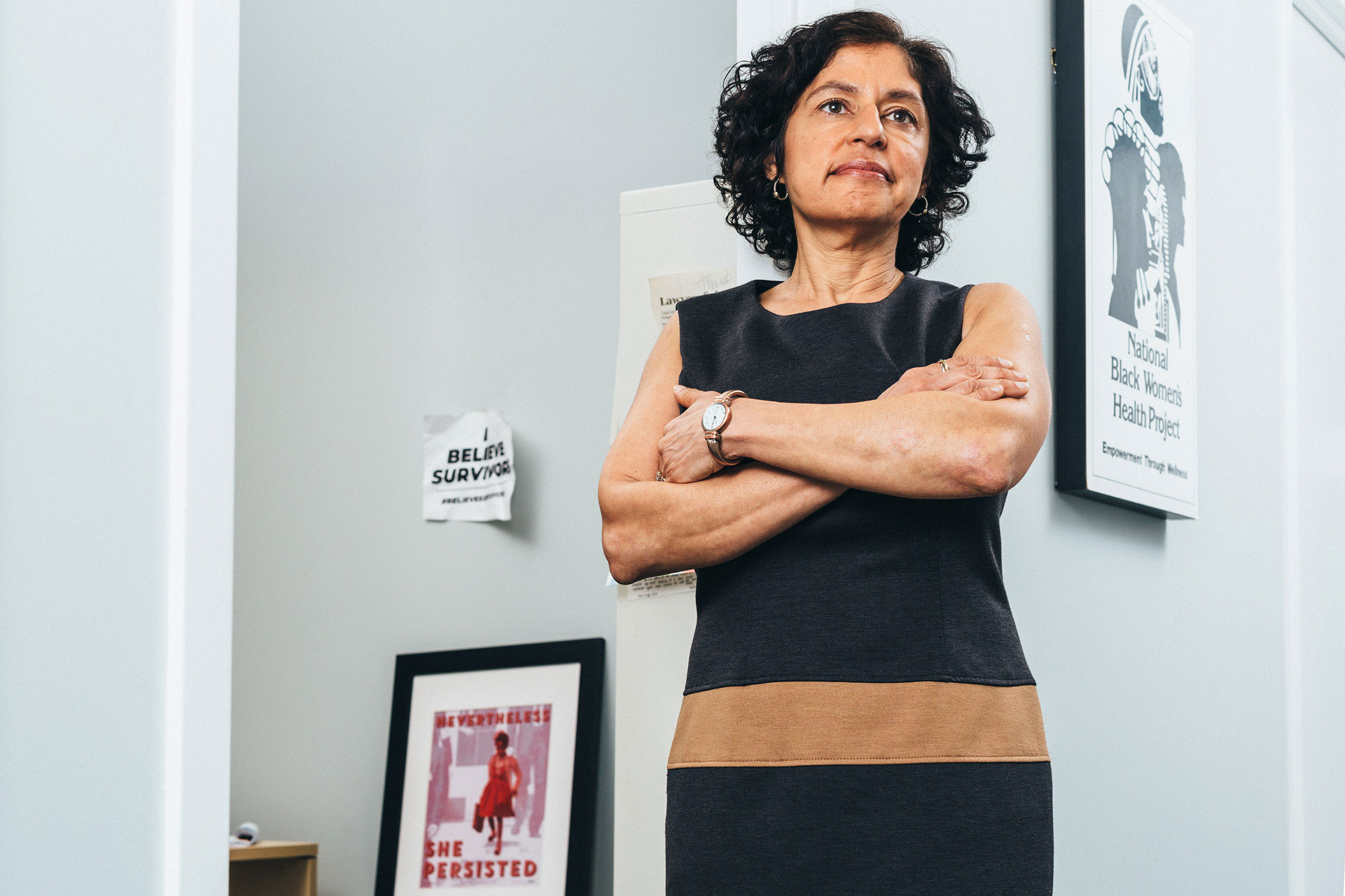 Sharyn Tejani, Director of the TIME'S UP Legal Defense Fund, standing with her arms crossed in her office.