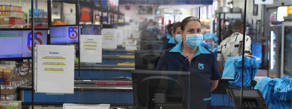 Grocery worker wearing a medical mask behind a register