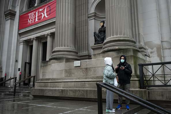Two tourists wear protective masks while standing in front of the Metropolitan Museum of Art