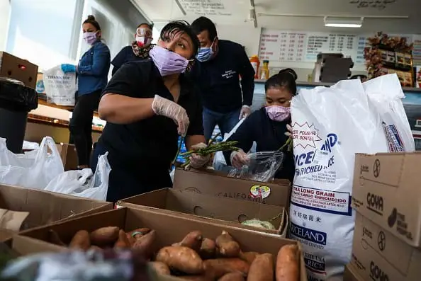 Workers wearing protective masks and gloves package food to distribute to food pantries.