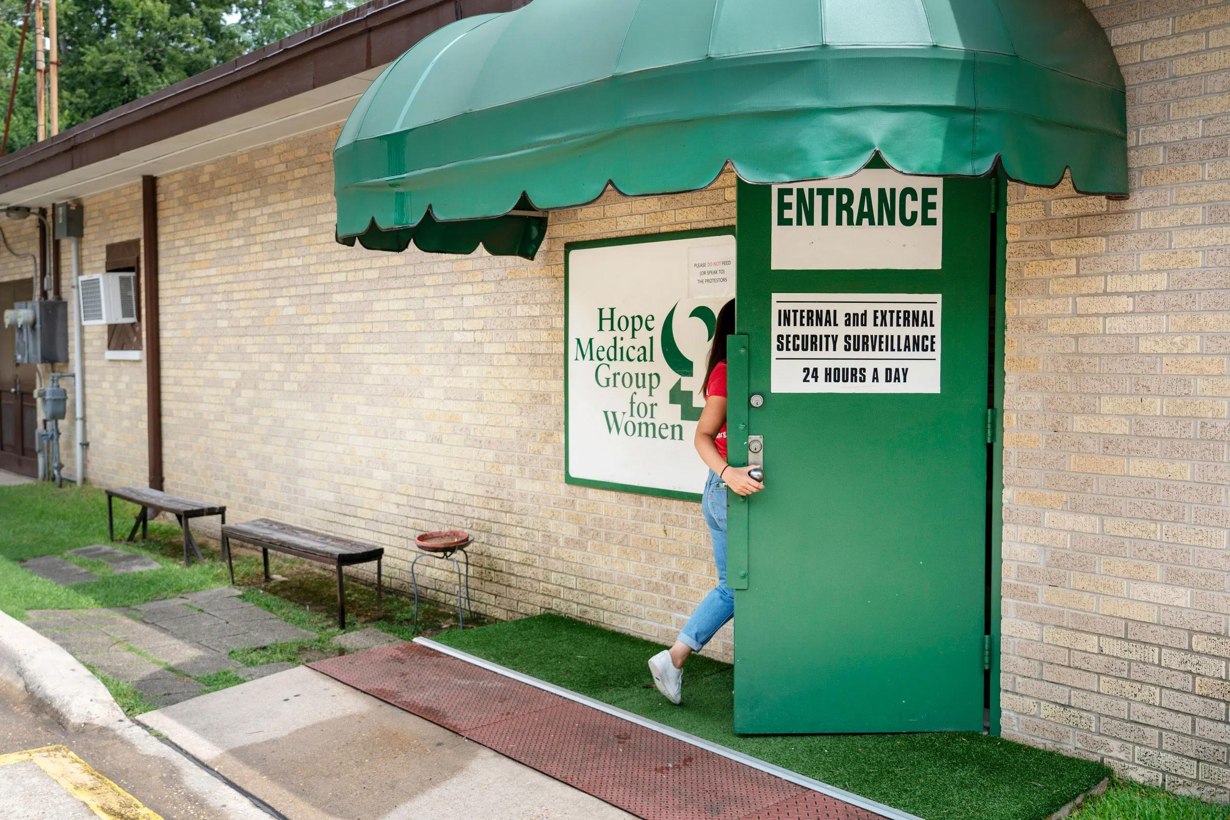 A woman entering the Hope Medical Group for Women under a green awning.