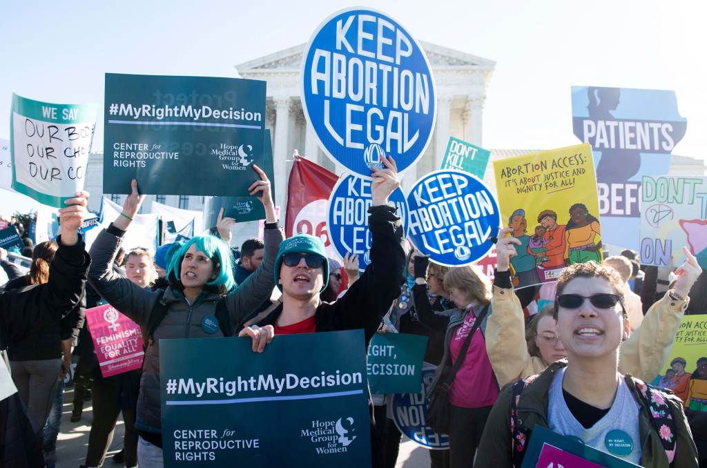 Abortion rights activists at a protest holding up signs.