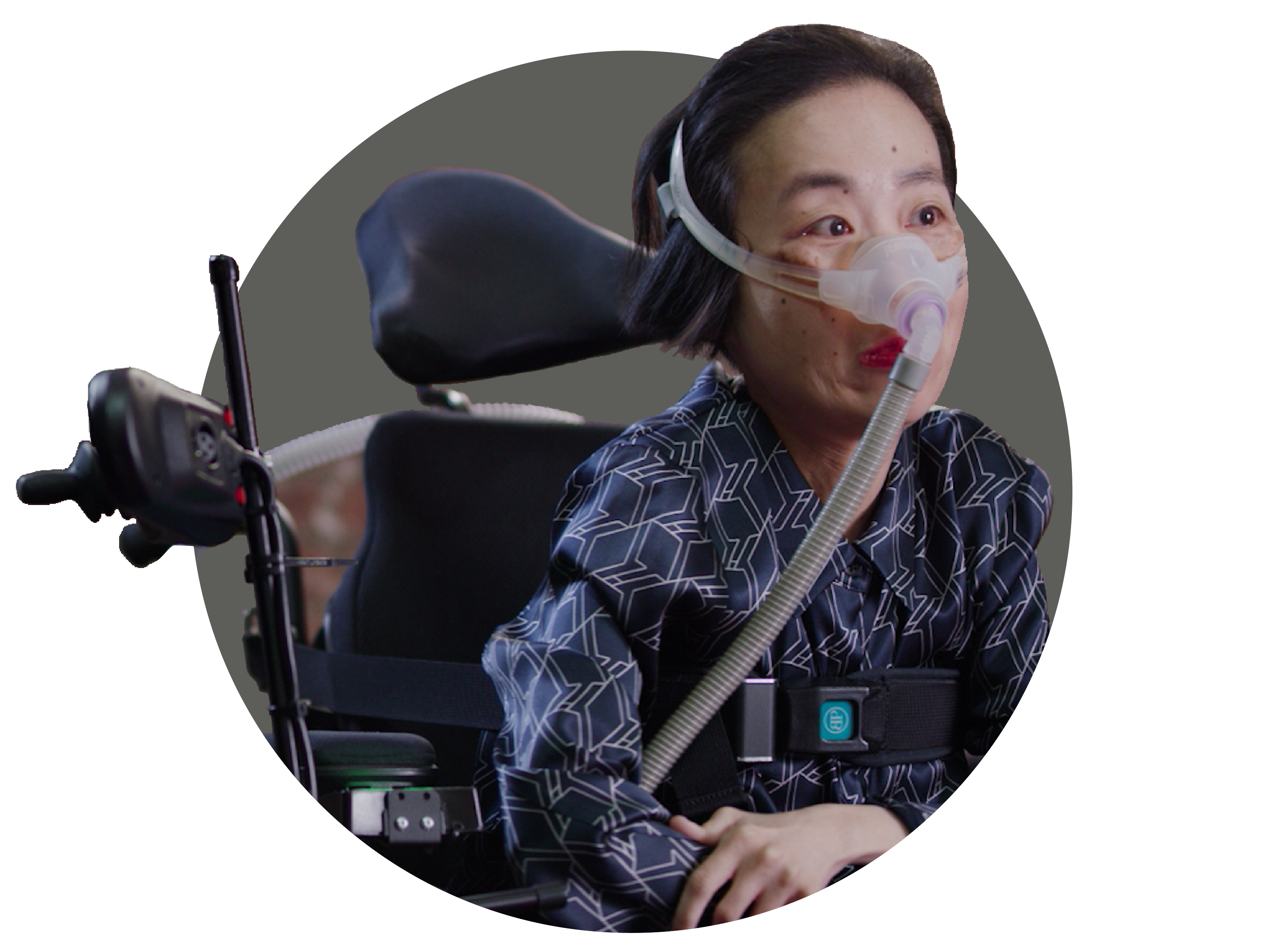 Alice Wong, an Asian American woman in a wheelchair wearing a mask over her nose attached to a tube for a BiPAP machine that helps her breathe. She is wearing a navy striped shirt and dark pants.