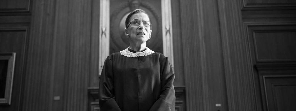 Ruth Bader Ginsburg in black judicial robe looks ahead at the bench inside the wood-paneled U.S. Supreme Court building in Washington D.C. Photo by Nikki Kahn/The Washington Post via Getty Images
