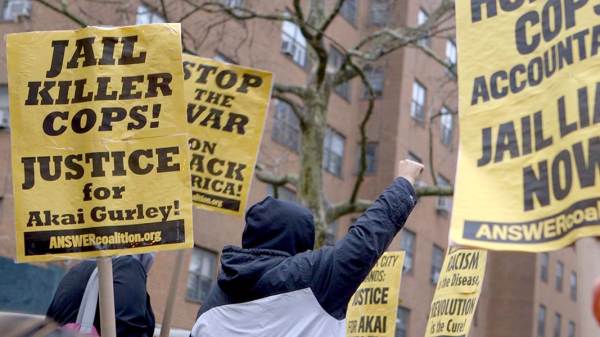 A yellow protest sign that says: "Jail Killer Cops! Justice for Akai Gurley" 