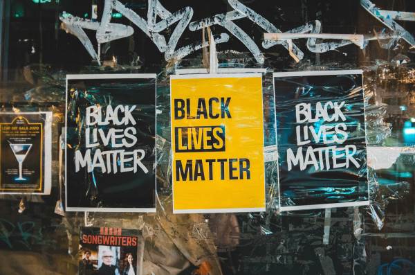 Black and yellow "Black Lives Matter" posters on a graffitied wall.