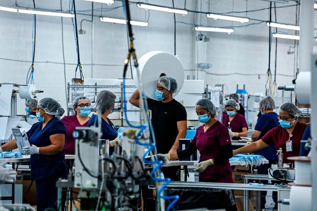 Group of workers wearing hair nets and n95 masks at a medical equipment factory in North Miami, Fla. Photo by CHANDAN KHANNA/AFP via Getty Images