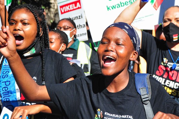 Young activists holding signs and South African flags cheer and march in Durban, South Africa.