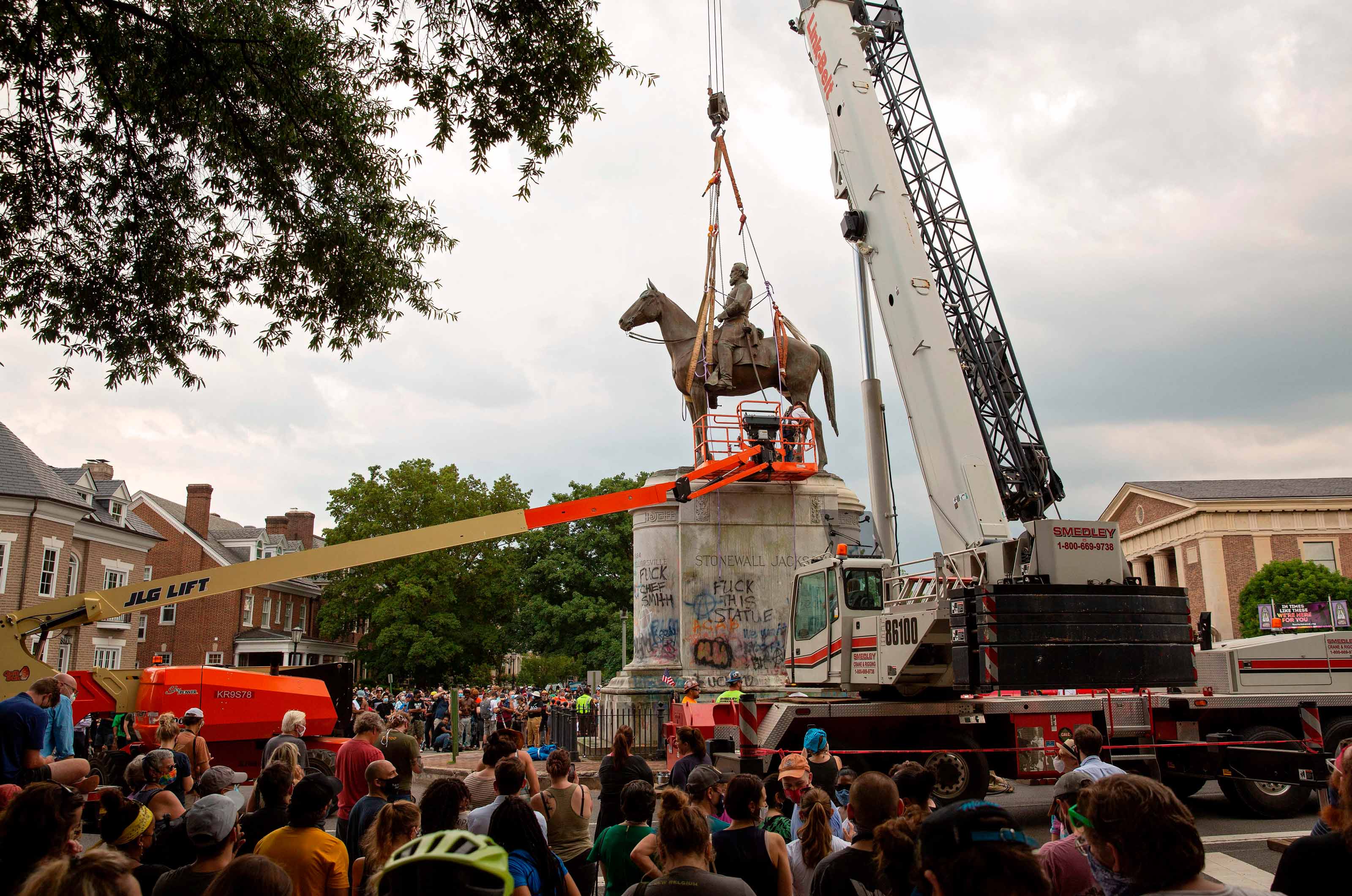 Bystanders watch as a crane removes the Stonewall Jackson statue from Monument Avenue in Richmond, Virginia.