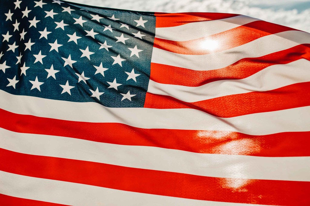 Closeup of an American Flag against a cloudy sky.