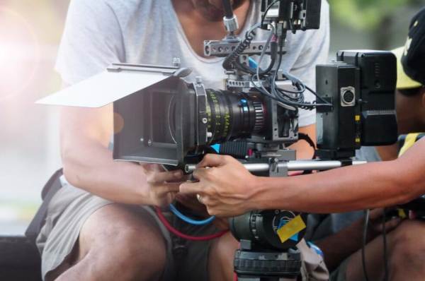 Two people working a motion picture camera.