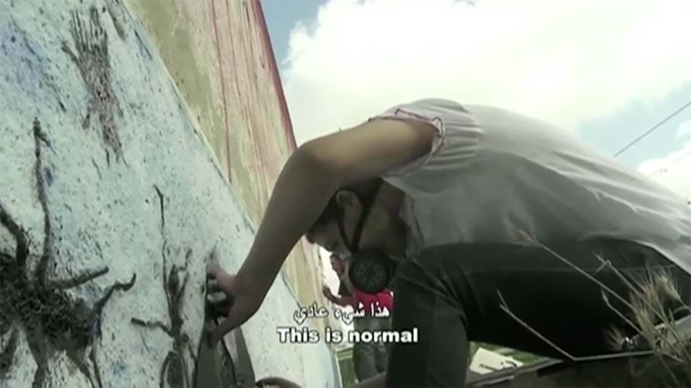 A man wearing a protective mask spray paints ants onto a white wall.