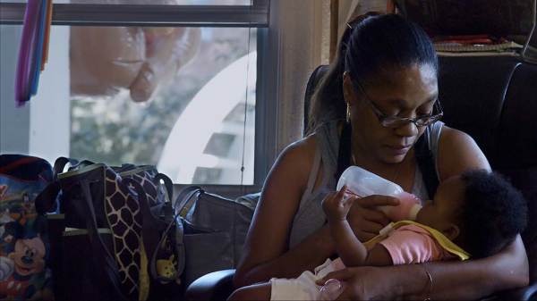 A photograph of a caregiver feeding a baby with a bottle