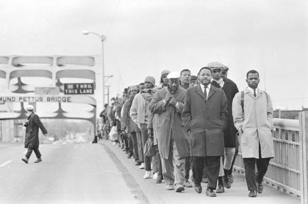John Lewis with fellow protestors at Edmund Pettus Bridge, in JOHN LEWIS: GOOD TROUBLE, a Magnolia Pictures release. © Alabama Department of Archies and History. Donated by Alabama Media Group. Photo by Tom Lankford, Birmingham News. Photo courtesy of Magnolia Pictures.
