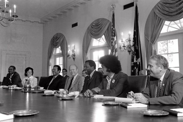 A black and white photograph of Vernon Jordan and others sitting at a table
