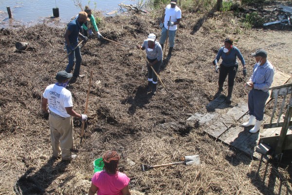 An aerial photo of individuals removing washed up debris post hurricane IDA in the “historic” Grand Bayou Village.