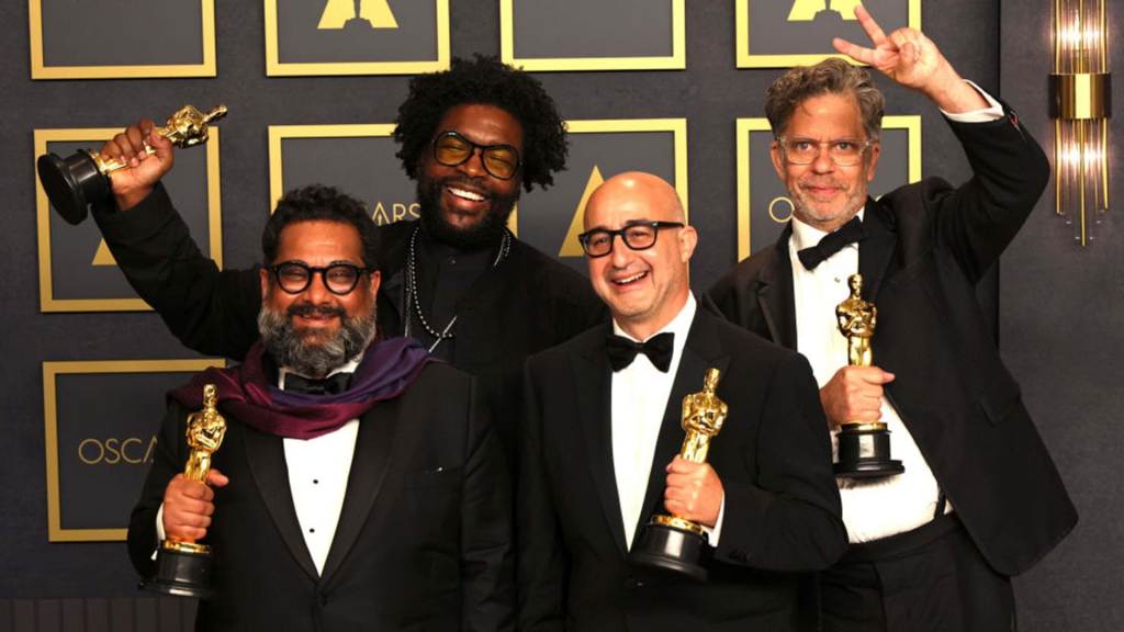 Joseph Patel, Ahmir "Questlove" Thompson, David Dinerstein and Robert Fyvolent, winners of Best Documentary Feature for "Summer of Soul (...Or, When the Revolution Could Not Be Televised),”. All four men are dressed in black tuxedos and holding their Oscars awards while standing in front of an Oscars backdrop.
