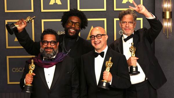  Joseph Patel, Ahmir "Questlove" Thompson, David Dinerstein and Robert Fyvolent, winners of Best Documentary Feature for "Summer of Soul (...Or, When the Revolution Could Not Be Televised),”. All four men are dressed in black tuxedos and holding their Oscars awards while standing in front of an Oscars backdrop.  