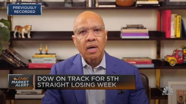 Darren Walker sitting in front of a book case  wearing a white shirt and blue suit coat